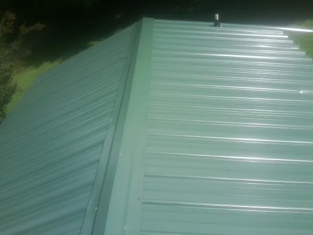 New green metal panels meeting at the ridge of a roof — Flat Roof Repair work by our crew in Zionsville